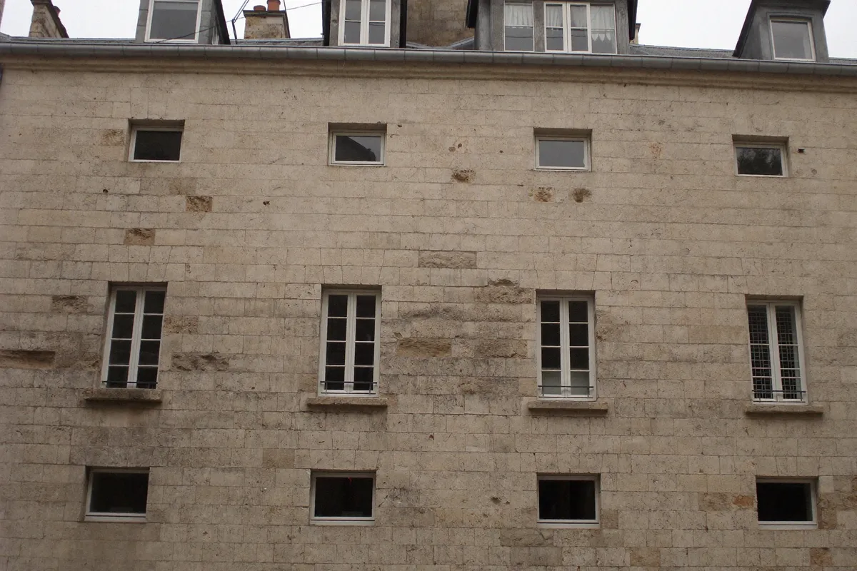 Façade ancienne et patinée d'un immeuble du centre historique de Paris, 4e