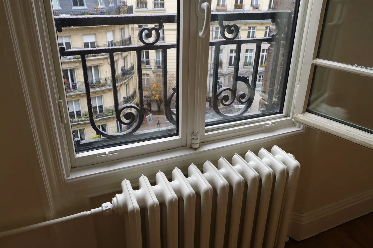 Fenêtre à double vitrage et radiateur moderne dans un appartement parisien rénové